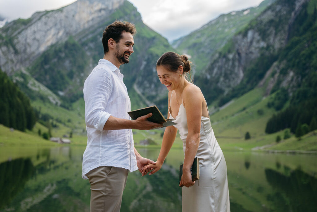 Bride and groom laughing as they read their vows to each other at Seealpsee; How to Elope in Switzerland