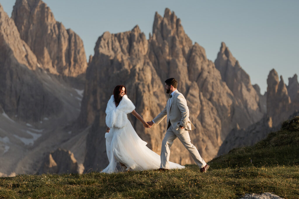 Bride leading groom in a hike across Cadini di Misurina. They wanted to book a cool elopement summer destination, so they decided to stay in the mountains of the Dolomites to avoid heatwaves and fires