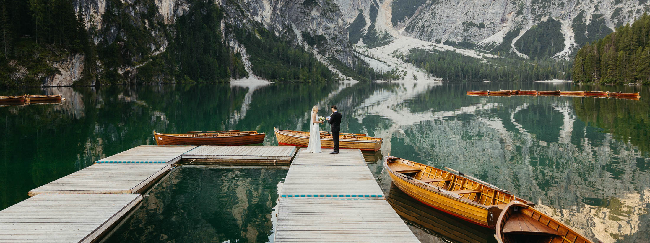Husband and wide exchanging vows at Lago di Braies. The Ultimate Elopement Guide