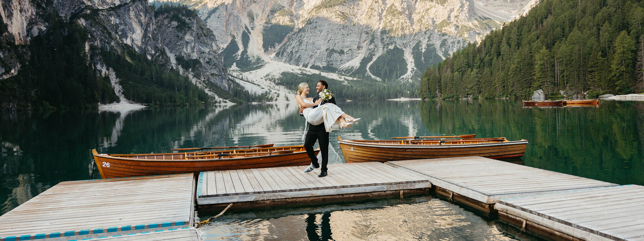 Bride and groom feeling comfortable posing for photos at Lago di Braies on the La Palifitta dock at sunrise