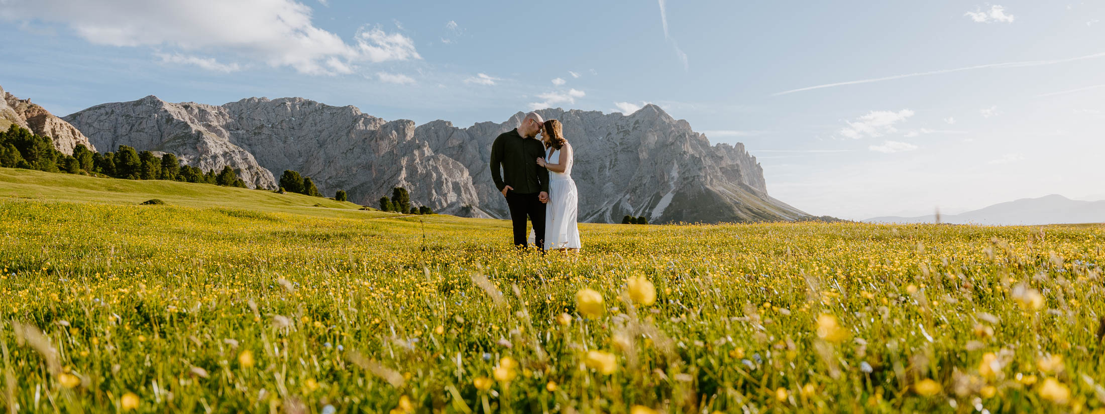 Bride and groom walking through wildflower field at sunset at Passo delle Erbe
