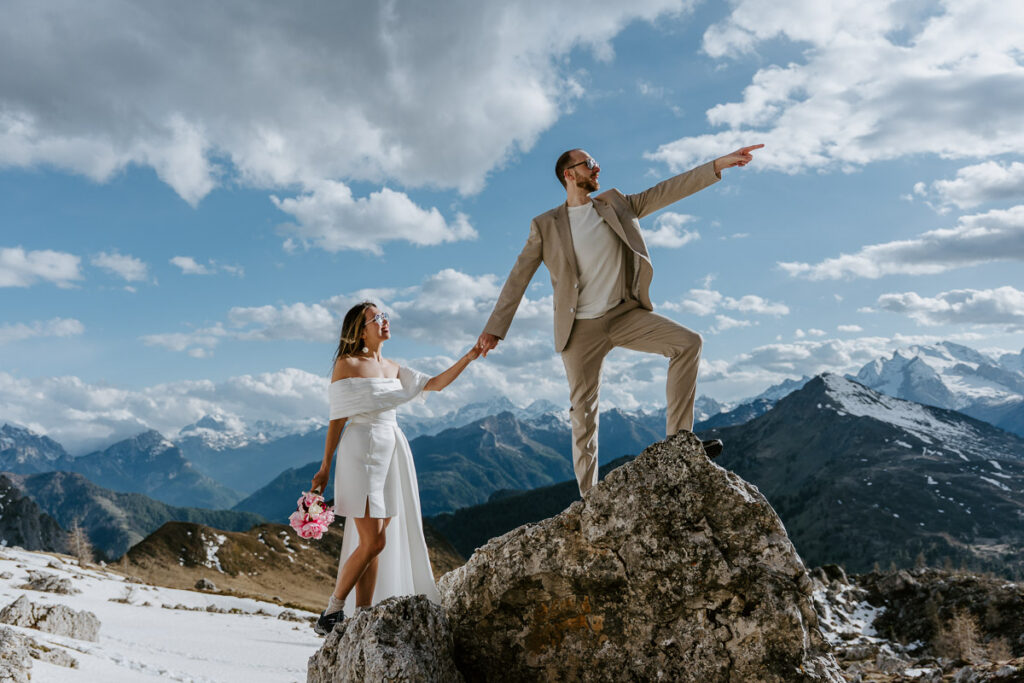 Bride and groom standing on a rock during their hike with snow all around. Things to do on your elopement day