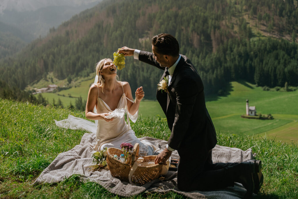Groom feeding bride grapes during their elopement at Val di Funes