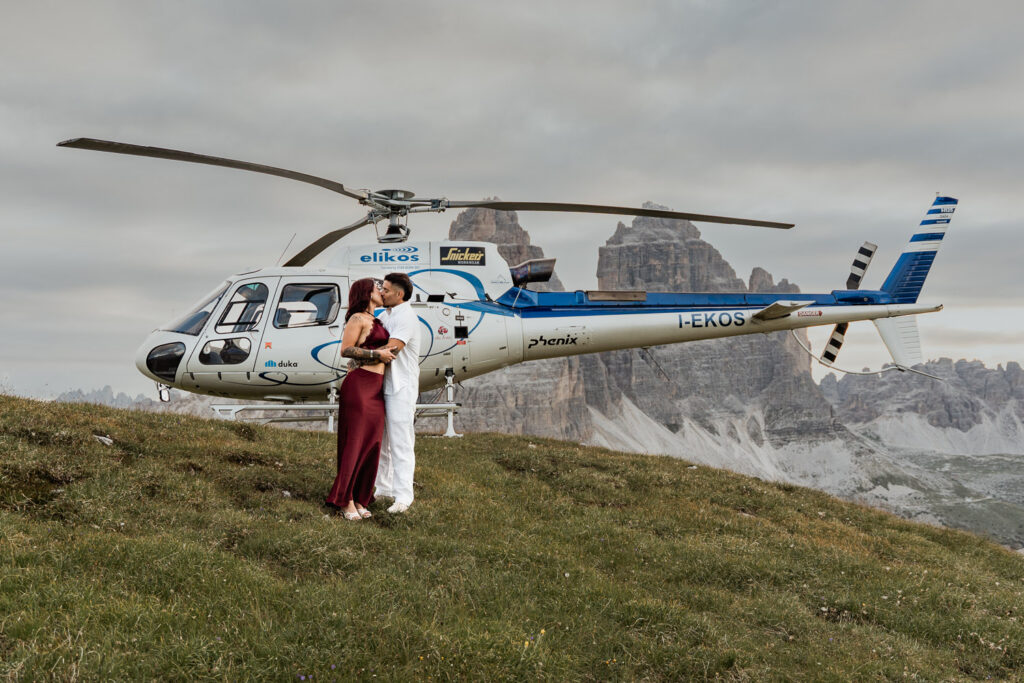 Plan helicopter proposal with fiancés kissing with Elikos in the background and Tre Cime