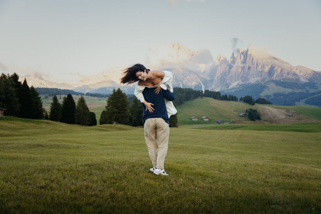 Man tossing wife around in circles in Alpe di Siusi as they feel comfortable posing for photos