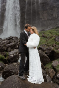 Bride and groom posing on a rock at Fossà on the Faroe Islands, touching foreheads together