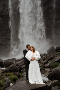 Bride and groom standing in front of Fossà, Faroe Island's largest waterfall