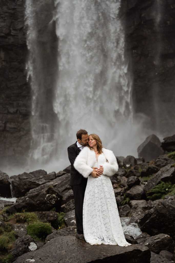 Bride and groom standing in front of Fossà, Faroe Island's largest waterfall