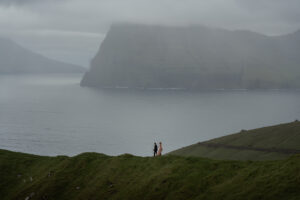 Bride and groom walking on ridge at Kallur during elopement on Faroe Islands