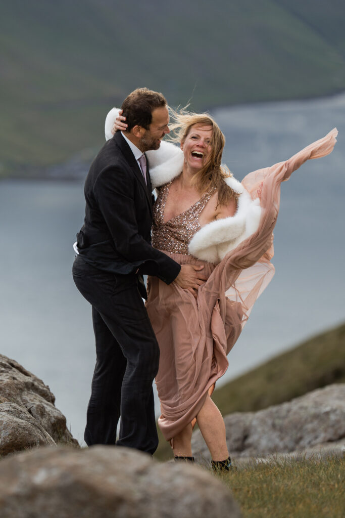 Bride laughing as her dress is picked up by the wind in Faroe Islands
