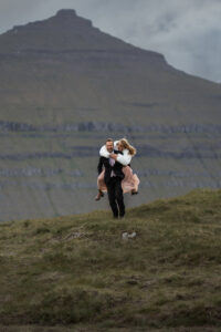 Groom giving bride piggy back ride after thier elopement at Klakkur on the Faroe Islands