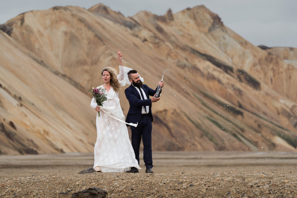 Bride and groom popping champagne in Landmannalaugar, Iceland. Why you should have a multi-day elopement