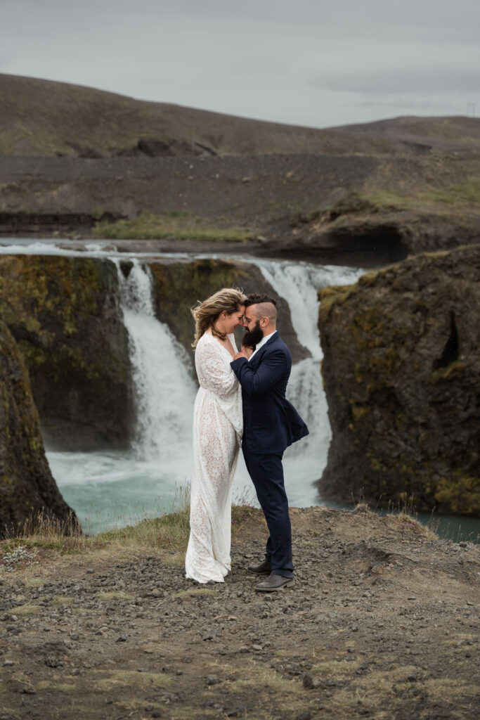 Bride and groom touching foreheads in front of Sigoldufoss waterfall; How to Elope in Iceland