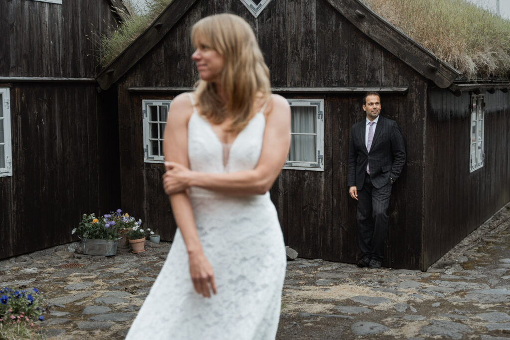 How to elope in the Faroe Islands: the ultimate guide. Bride and groom standing against typical Faroese houses in Tórshavn with grass roofs