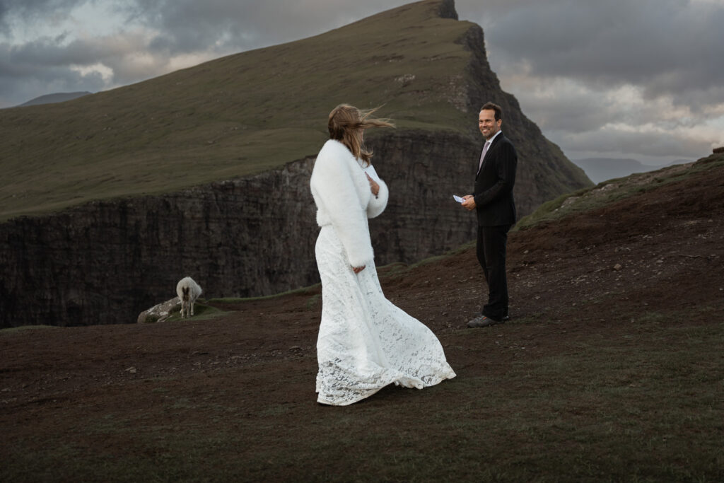 Bride looking back at groom with dramatic cliff and ocean background of Traelanipa