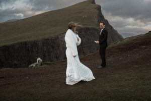 Bride looking back at groom with dramatic cliff and ocean background of Traelanipa