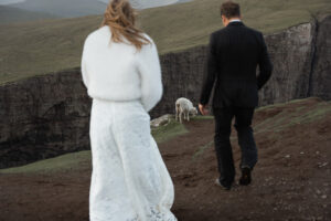 Sheep between bride and groom during their elopement and vow renewal on Trælanípa, Faroe Islands