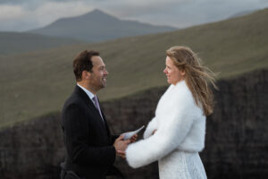 Groom reads vows to bride at Trælanípa during their vow renewal on the Faore Islands