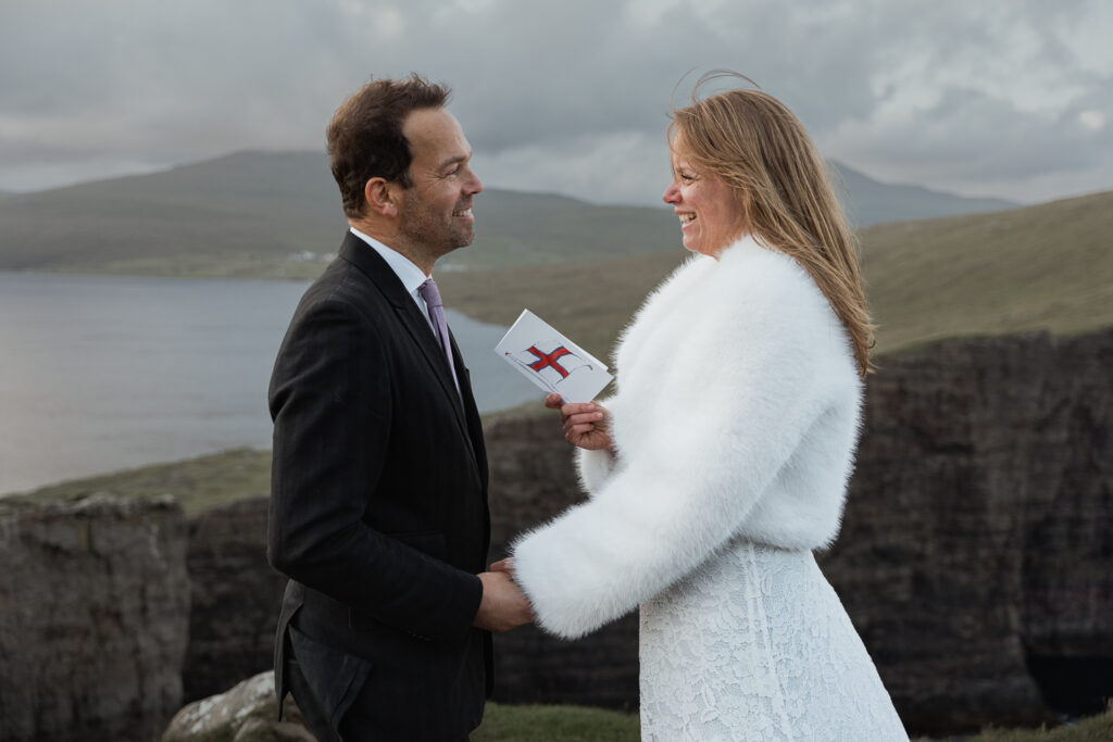 Bride reads vows to groom on Faroese card at Trælanípa on Faroe Islands for their elopement