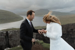 Bride and groom exchange rings overlooking cliffs of Trælanípa on Faroe Island