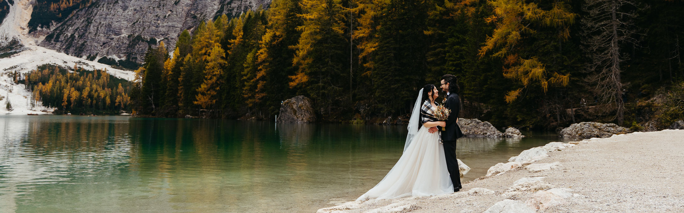 Bride and groom at Lago di Braies in autumn on moody day, one of the top places to elope in autumn