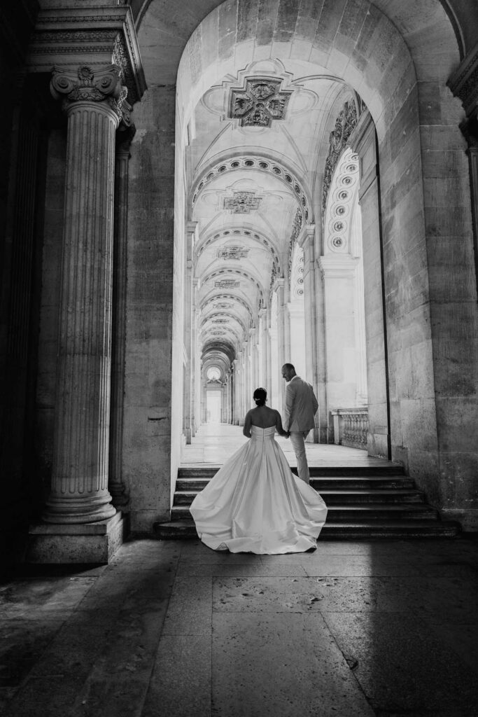 Bride and groom in black and white at the Louvre with beautiful contrasting hallway; How to Elope in Paris