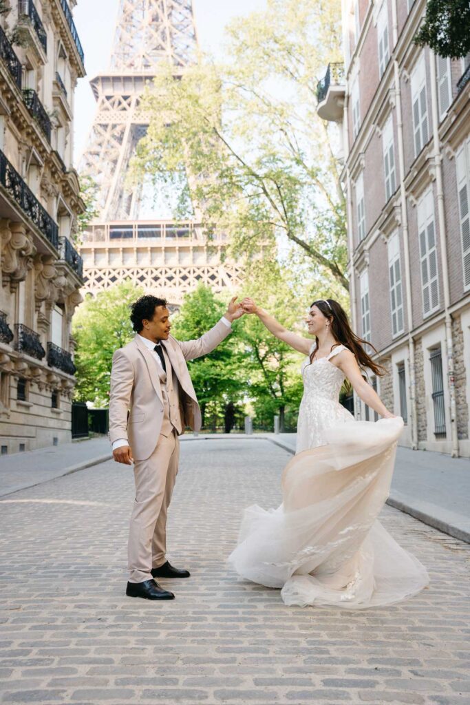 Bride and groom in front of Eiffel Tower while spinning; How to Elope in Paris