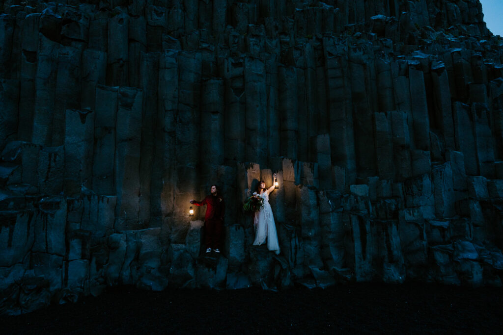 Bride and groom in the dark with lanters at Reynisfjara beach. Best places to elope in Icealnd.