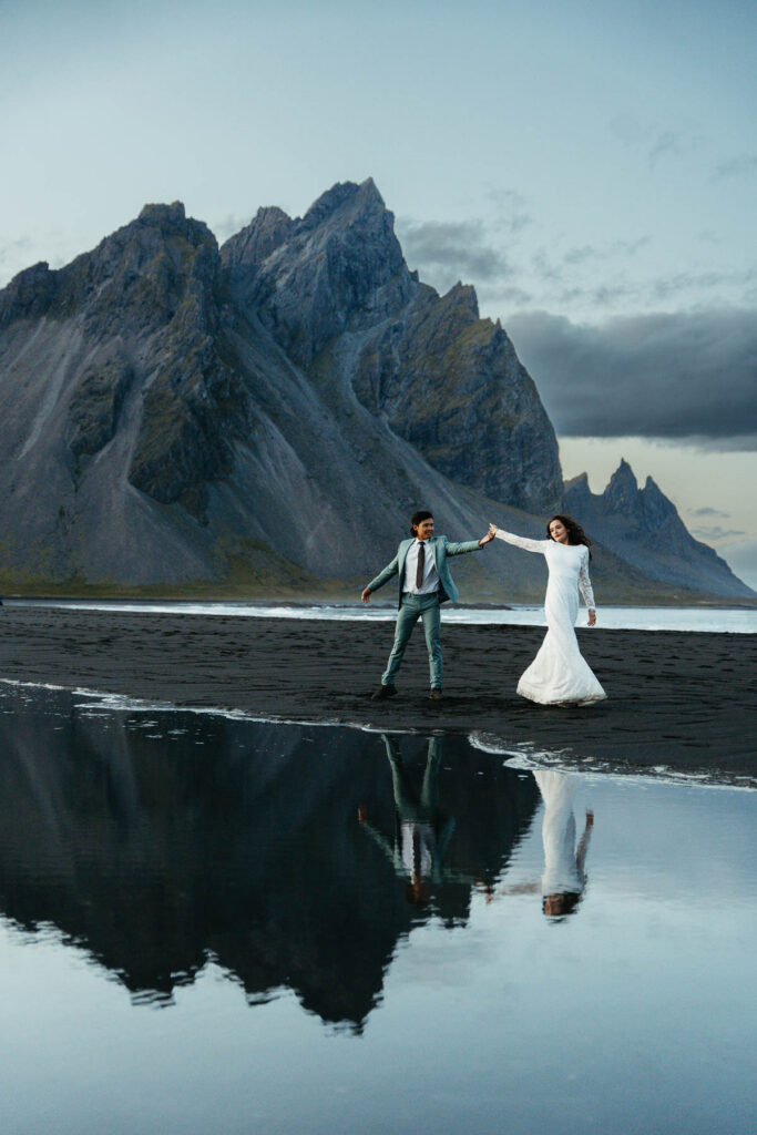 Bride and groom with reflections in the pond at Stokksnes in Iceland during their elopement